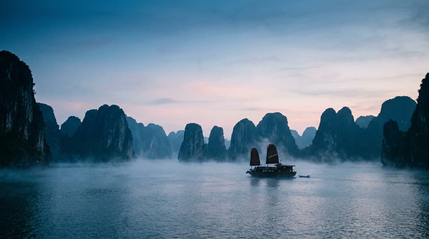 A junk boat at dawn among the limestone karsts of Ha Long Bay