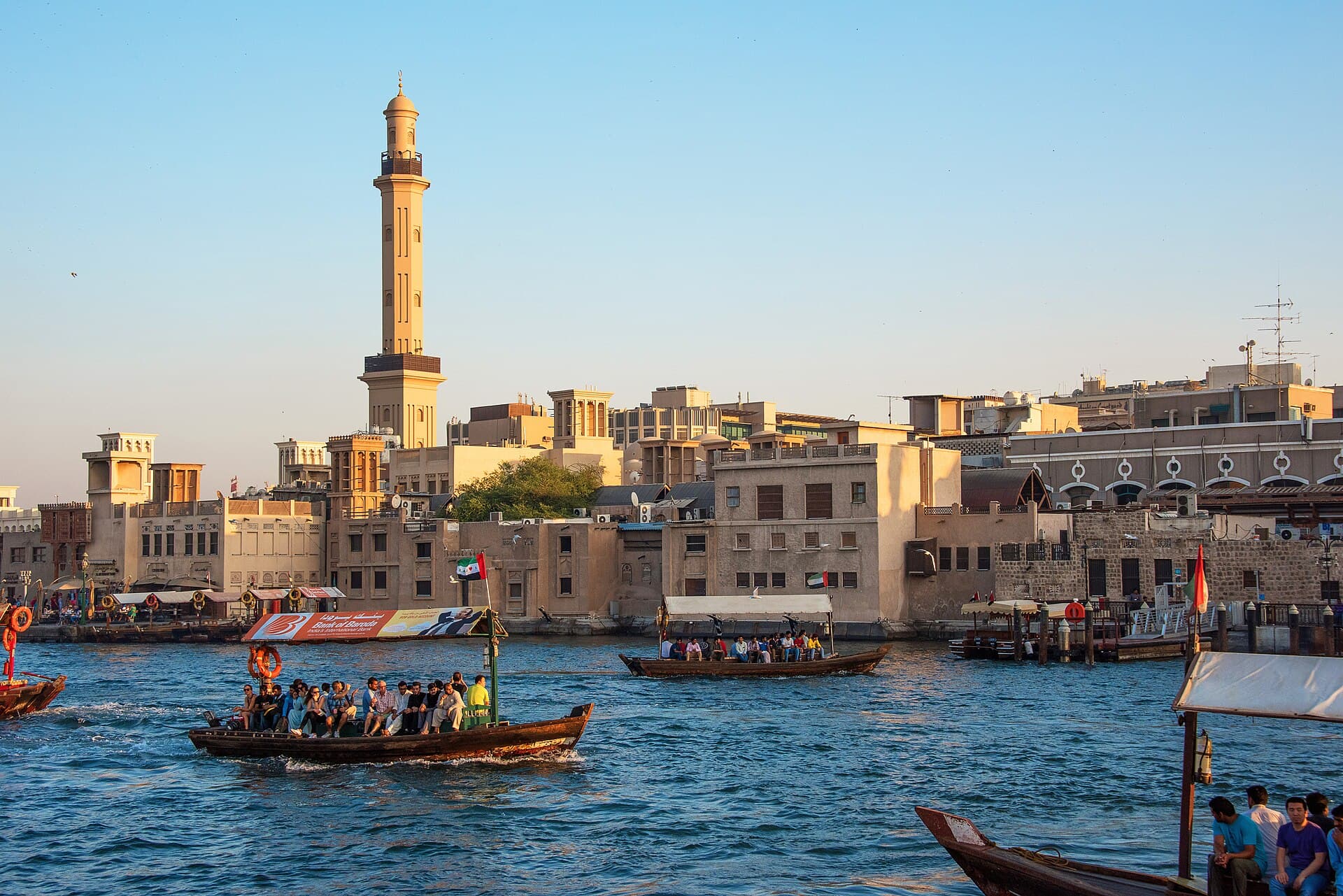 Wooden abra boats crossing Dubai Creek with the old town behind