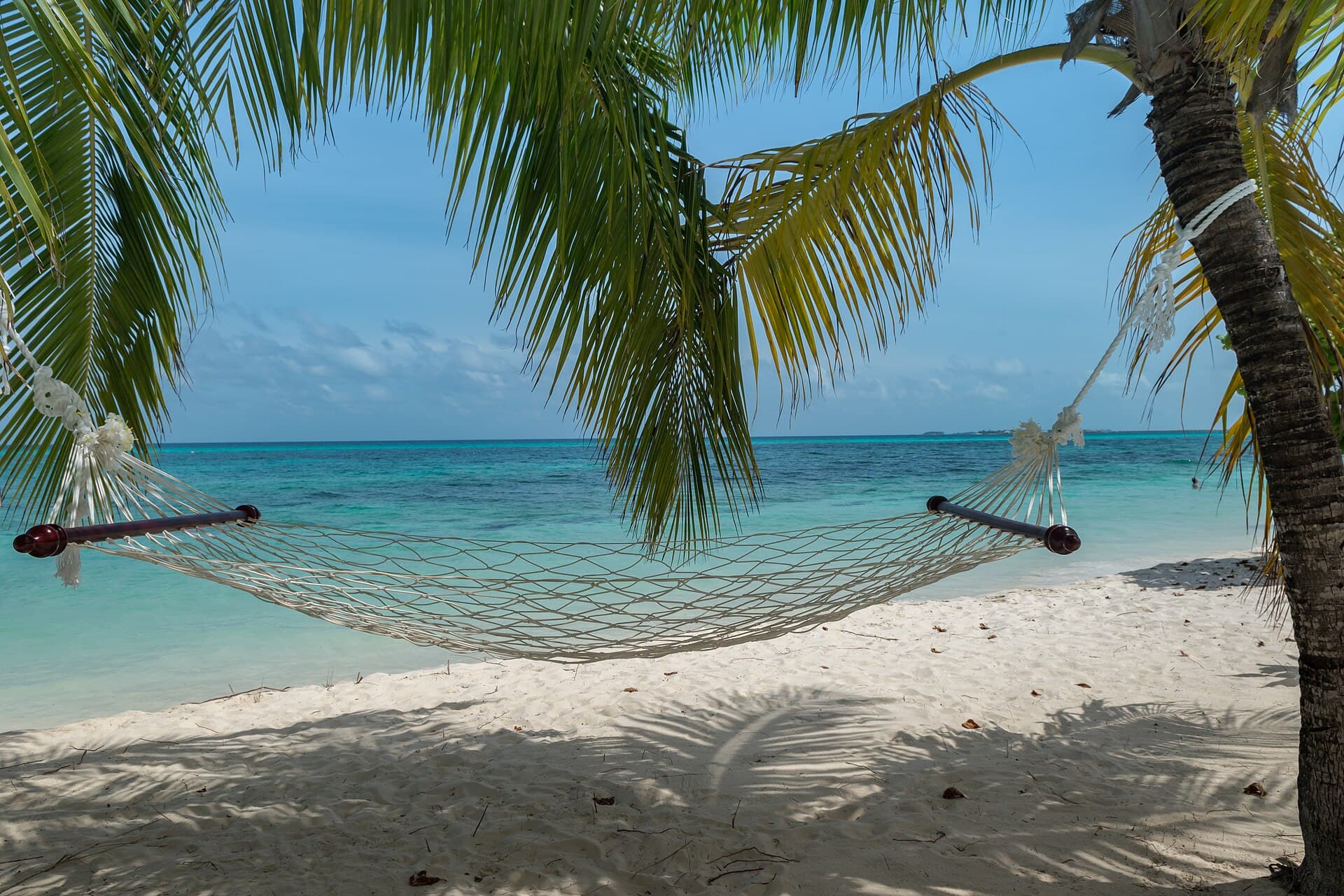 A hammock over the shallows of a Maldives beach